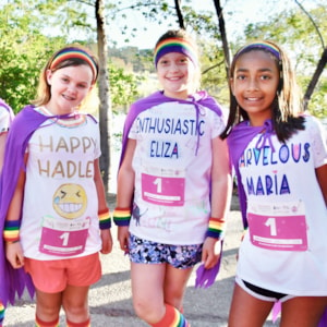 Girls on the Run participants stand back to back with a teammate smiling.